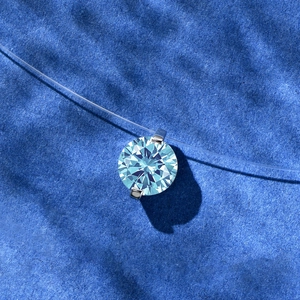 Macro shot of 2ct round cut blue diamond pendant on invisible fishing line necklace