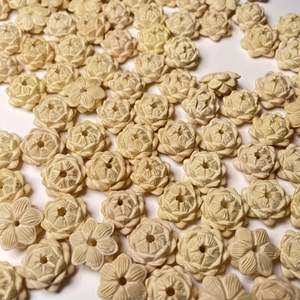 Macro shot of hand-carved boxwood lotus flower beads with natural textures on white backdrop