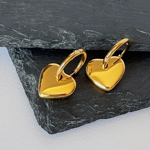 Detailed close-up of 18k gold plated heart earrings on a minimalist stone background