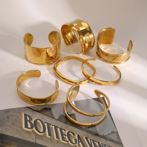 Detail view of gold chunky bangles with polished and hammered textures in artistic lighting