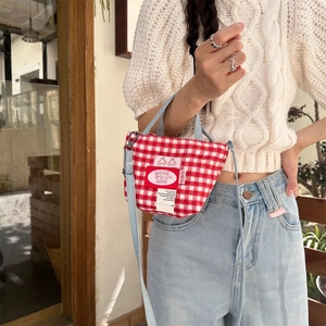 Macro detail of red and white gingham mini tote with denim straps and cherry patch decoration