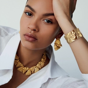 Close-up of gold lava texture cuff bracelet and chunky earrings set for elegant look
