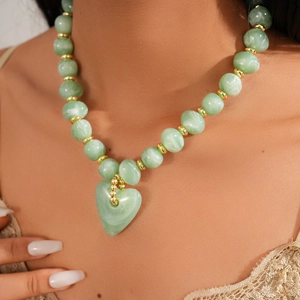 Close-up of green marble-textured beaded necklace with a gold-accented heart pendant