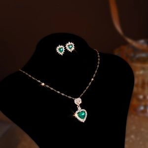 Detail of rose gold heart pendant necklace and earrings with emerald green crystals