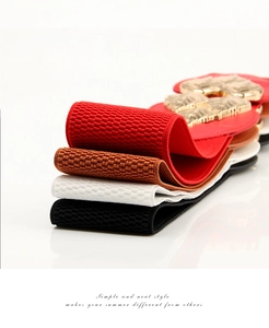 Detail of four elastic belts in red, brown, white, and black with ornate gold leaf buckles