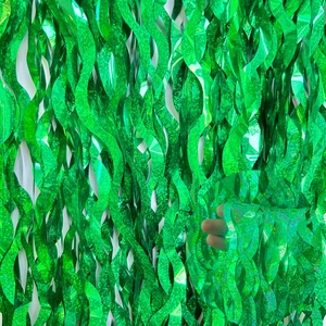 Detailed close-up of green shimmering S-shaped fringe curtain with metallic texture