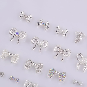 Macro de charmes d'ongles en forme de nœud avec perles et strass sur fond miroir