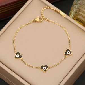 Detail of gold heart evil eye bracelet with enamel charms and lobster clasp on jewelry box