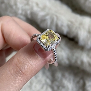 Close-up of radiant cut yellow gemstone ring with pavé diamond halo and band