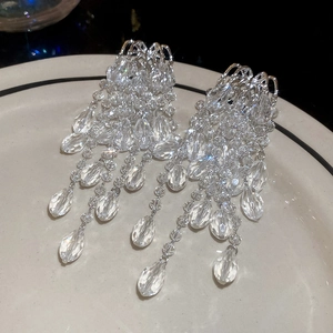 Detail shot of cascading crystal drop fringe earrings displayed on a white ceramic plate