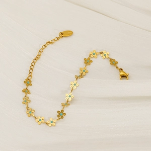 Golden stainless steel flower bracelet with turquoise centers on a soft beige fabric