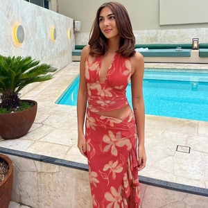 Détail du haut dos nu à fleurs rouges et jupe fendue près d'une piscine ensoleillée