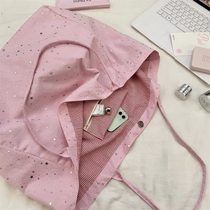 Pink canvas tote bag interior with red stripes and large capacity shown on a bed