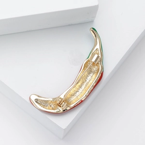 Macro shot of the golden enamel chili brooch back with a secure metal safety pin