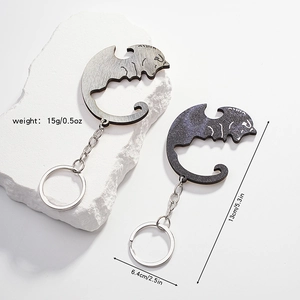 Detail view of cat keychains with dimensions 13cm and 6.4cm on a white stone base
