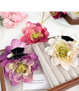 Detailed view of floral hair claws in purple, pink and white on a velvet tray