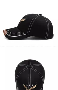 Detail view of black baseball cap with white contrast stitching and eagle wing embroidery
