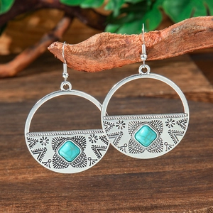 Detailed close-up of bohemian hollow round earrings with turquoise on a wooden background