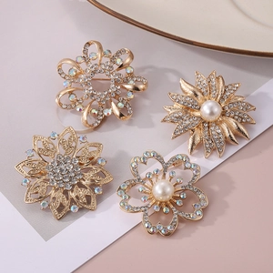 Vue détaillée de quatre broches fleurs dorées avec des strass étincelants et des perles