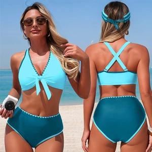 Light blue halter bikini set with high-waisted teal bottoms shown on a sunny beach