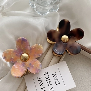 Floral acetate hair claw clips with marble and tortoise patterns on silk fabric background