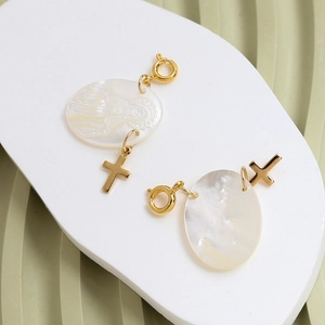 Detail of a white shell pendant with gold cross and relief on a ceramic tray