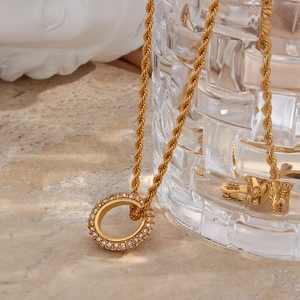 Macro shot of gold twist chain necklace with sparkling zircon-encrusted ring pendant