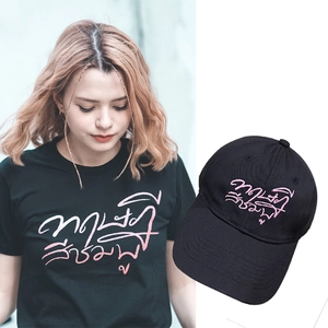 Detailed view of black cotton baseball cap with pink Thai script embroidery