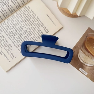 Dettaglio di una pinza per capelli blu opaca di grandi dimensioni su un libro