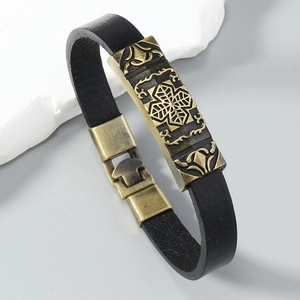 Macro shot of retro black leather bracelet with bronze Celtic knot charm on stone