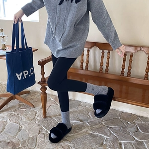 Detail of plush black fuzzy slippers with thick soles and double straps on a model