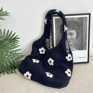 Detail of navy plush tote bag with white flower embroidery and black checkered lining