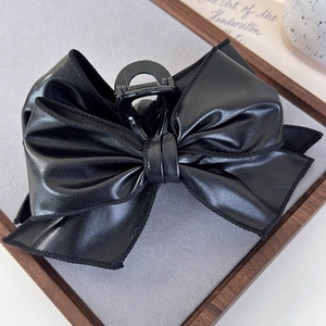 Detail of vintage black leather bow hair claw clip with striped texture for women