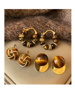 Detailed view of vintage gold tiger eye earrings on warm brown knit fabric backdrop