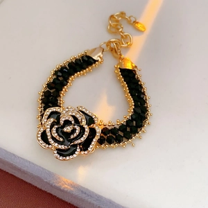 Close-up of gold rose bracelet with black petals, diamond edges and double-row beads