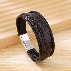 Detail of brown braided PU leather bracelet with silver magnetic alloy clasp on wood