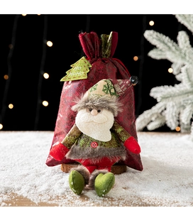Sac cadeau de Noël avec père Noël en peluche sur fond en bois enneigé et lumières douces