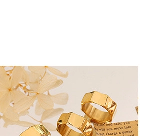 Close-up of a geometric knotted gold ring displayed on vintage paper with dried flowers