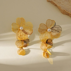 Detailed close-up of 3D gold flower earrings featuring white pearls and metallic finish