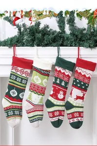 Close-up of four knitted Christmas stockings with snowflake and snowman patterns on a fireplace