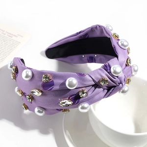 Détail d'un serre-tête nœud violet avec cœurs, perles blanches et strass brillants