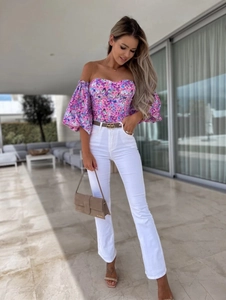 Close-up of floral off-shoulder top paired with a white high-waist pant and leather belt