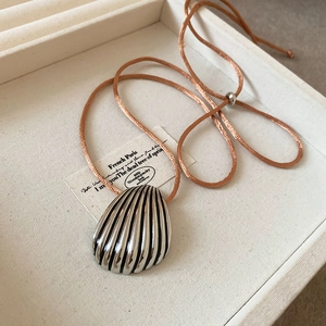 Detailed close-up of shell pendant necklace with pink silk cord and silver slider