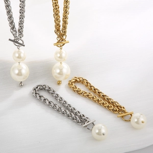 Elegante Edelstahl-Schmucksets in Gold und Silber mit Perlenanhängern auf weißem Stoff