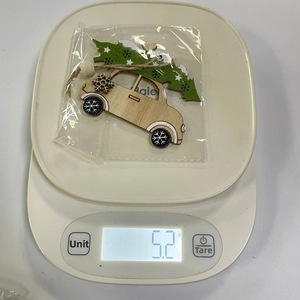Carrying a Christmas tree wooden ornament on electronic scale showing weight of 5.2g