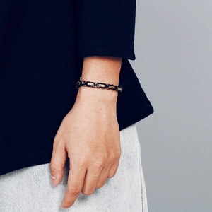 Detail of two-tone black and gold titanium steel chain bracelet worn on a male wrist