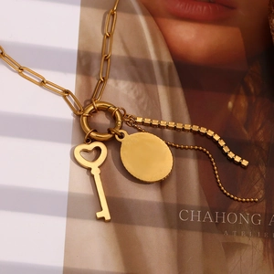Detail of 18K gold plated paperclip chain necklace with heart key and disc pendants