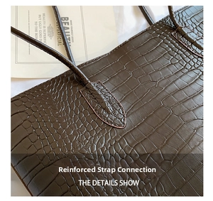Close-up of reinforced strap stitching on dark brown crocodile pattern tote bag