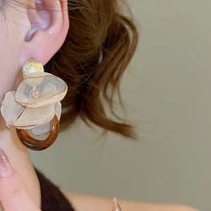 Close-up of floral fabric earrings with amber resin ring shown on model ear