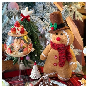 Standing plush gingerbread man toy with top hat and scarf on Christmas festive tabletop